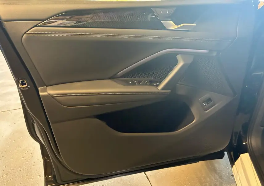 Vue intérieure côté gauche de la porte avant noire du Volkswagen Tiguan 2026 avec commandes de vitres et poignée intégrée.