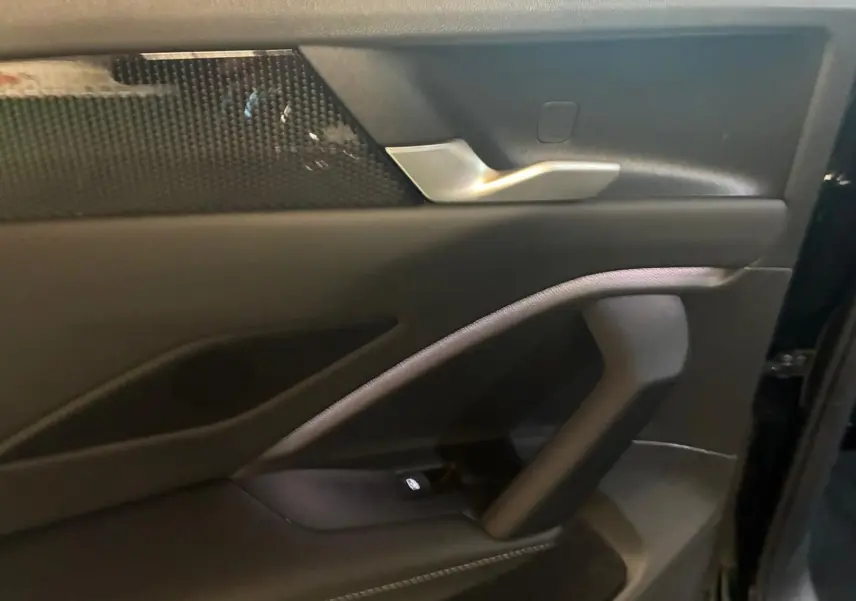 Gros plan sur la porte intérieure côté droit du Volkswagen Tiguan noir avec poignée argentée et insert décoratif noir.