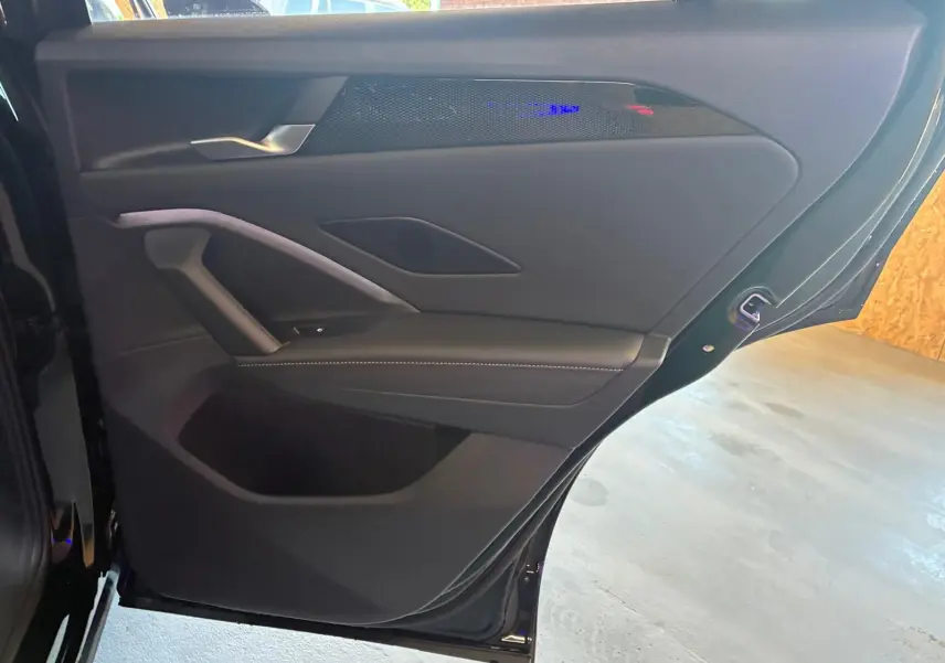 Vue intérieure côté gauche de la porte arrière noire grenadilla métal du Volkswagen Tiguan 2026 avec garniture en tissu et cuir.