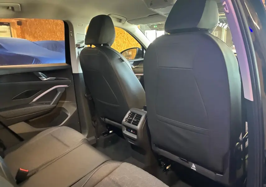 Vue intérieure arrière du Volkswagen Tiguan 2026 noir Grenadilla, sièges en tissu et cuir, avec commandes de climatisation arrière.