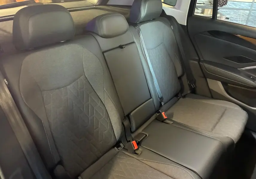 Vue intérieure des sièges arrière du Volkswagen Tiguan 2026, revêtement tissu et cuir noir avec surpiqûres contrastantes.