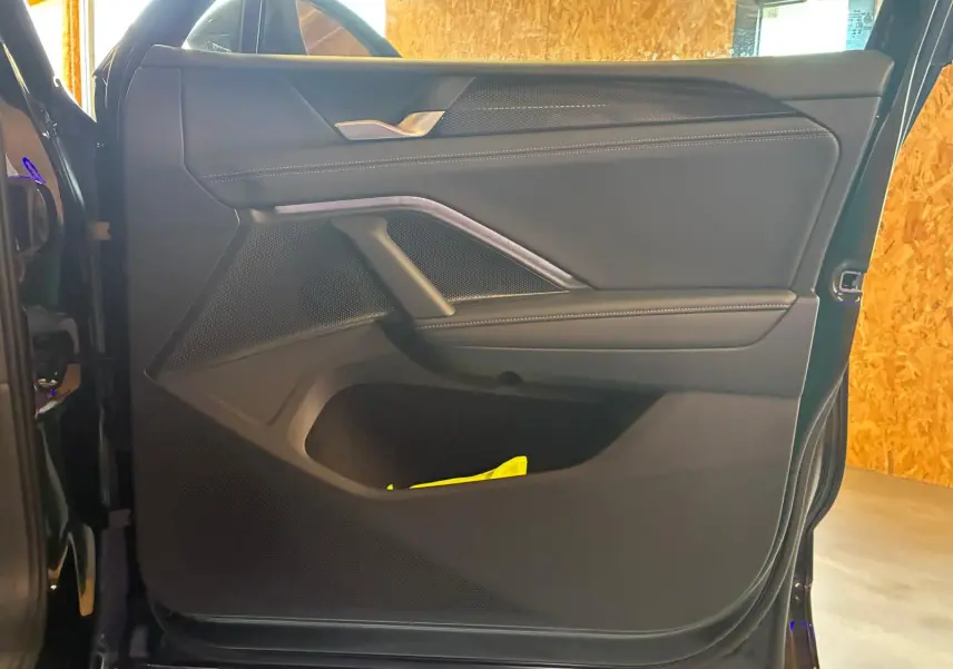 Vue intérieure de la porte avant gauche du Volkswagen Tiguan noir Grenadilla avec garniture en tissu et surpiqûres blanches.