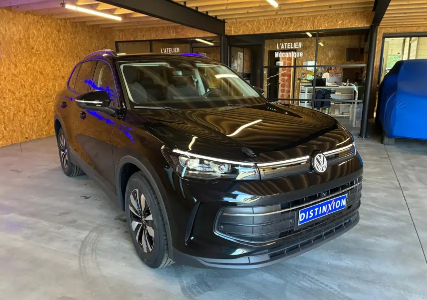 Volkswagen Tiguan 1.5 TSI noir grenadilla métal, vue 3/4 avant droit en intérieur d'atelier.