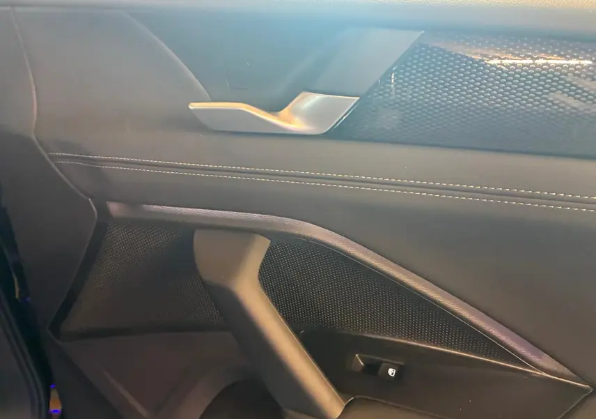Détail de la porte intérieure côté gauche du Volkswagen Tiguan noir Grenadilla, avec poignée argentée et surpiqûres blanches.