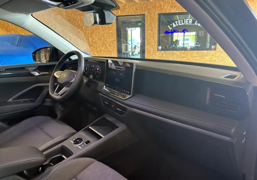 Vue intérieure côté conducteur du Volkswagen Tiguan 2026 noir Grenadilla, avec tableau de bord numérique et écran tactile central.