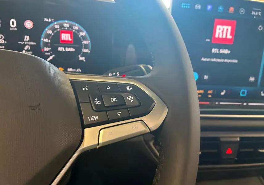 Gros plan sur le volant noir du Volkswagen Tiguan 2026 avec commandes multifonctions et tableau de bord digital lumineux.