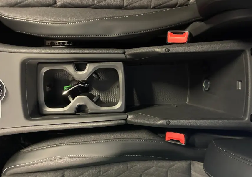 Vue plongeante sur la console centrale noire du Volkswagen Tiguan 2026 avec porte-gobelets et accoudoir en cuir.