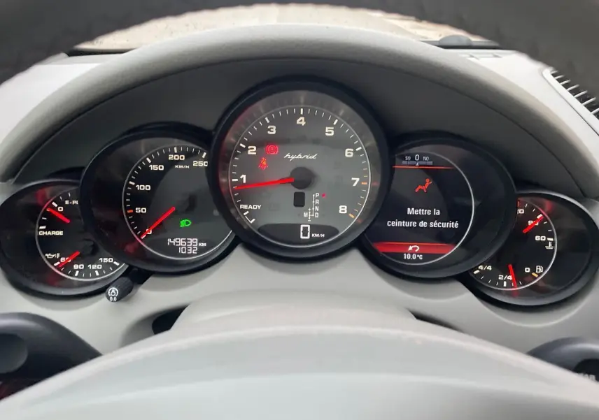 Vue du tableau de bord du Porsche Cayenne S Hybrid 2010 avec compteurs ronds et affichage digital au centre.