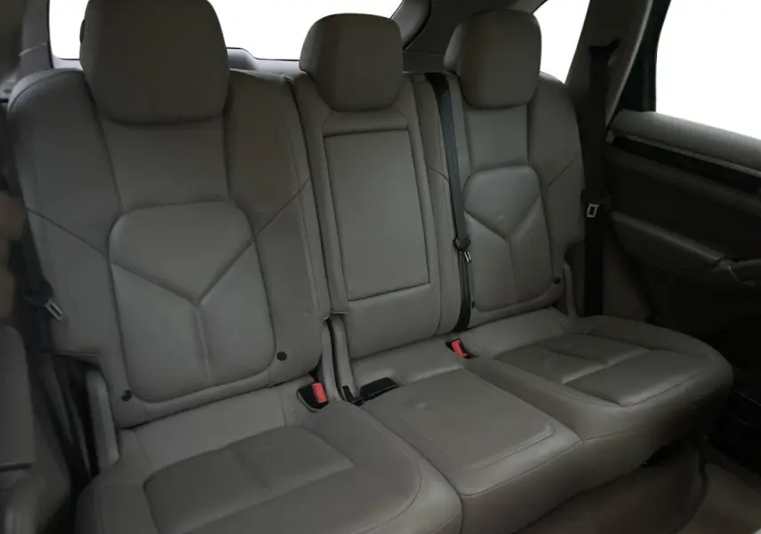 Vue intérieure des sièges arrière en cuir gris du Porsche Cayenne S Hybrid 2010, avec accoudoir central relevé.