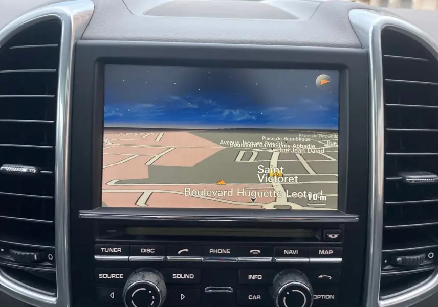 Écran de navigation du tableau de bord d'un Porsche Cayenne S Hybrid gris de 2010, avec commandes intégrées.