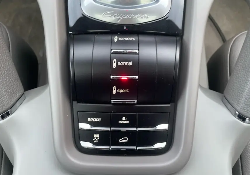 Gros plan sur la console centrale du Porsche Cayenne S Hybrid 2010 gris, avec mode sport activé et commandes de conduite.