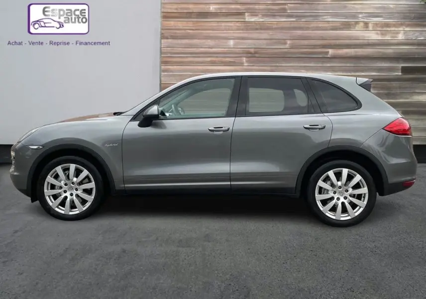 Profil côté gauche d'un Porsche Cayenne S Hybrid gris 2010 avec jantes alliage et badge hybrid visible sur l'aile avant.