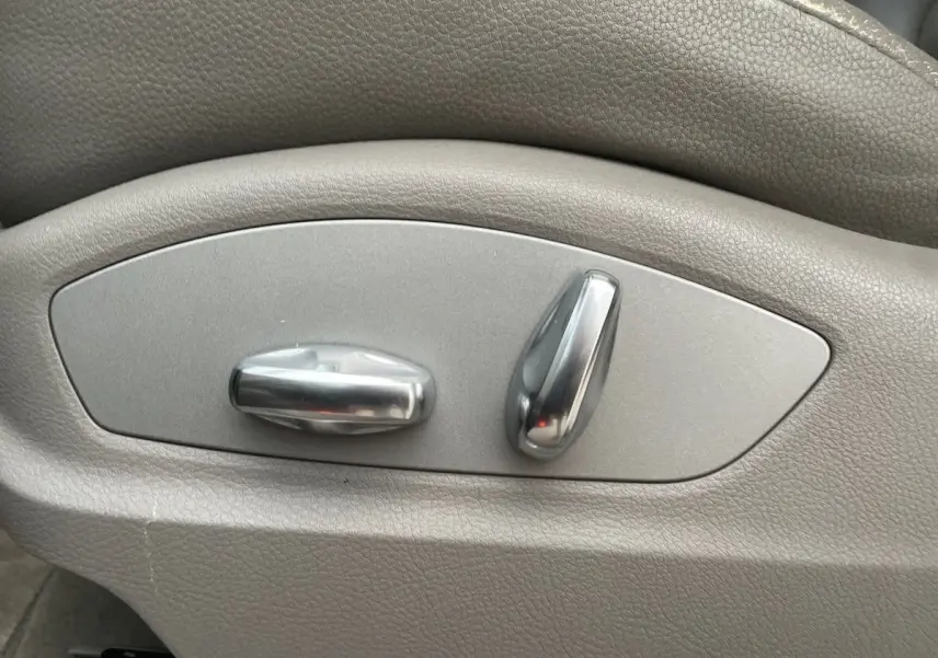 Gros plan sur les commandes de réglage électrique du siège en cuir gris du Porsche Cayenne S Hybrid 2010.