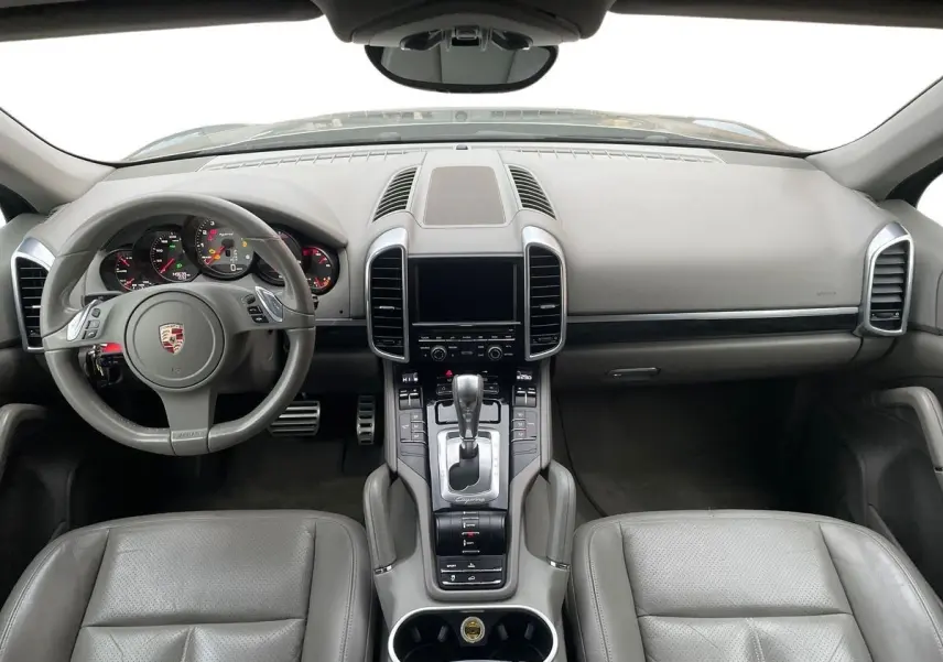 Intérieur gris du Porsche Cayenne S Hybrid 2010 vu de face, avec tableau de bord et console centrale détaillés.