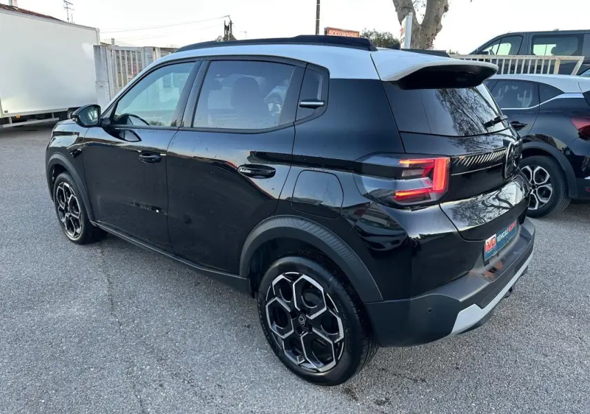 Vue 3/4 arrière droite d'une Citroën C3 Turbo noire avec jantes alliage 17 pouces et barres de toit visibles.