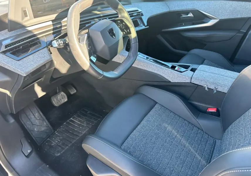 Vue intérieure côté conducteur du Peugeot 3008 Hybrid 145 e-DCS6 Allure 2025, avec sellerie mixte cuir et tissu gris.