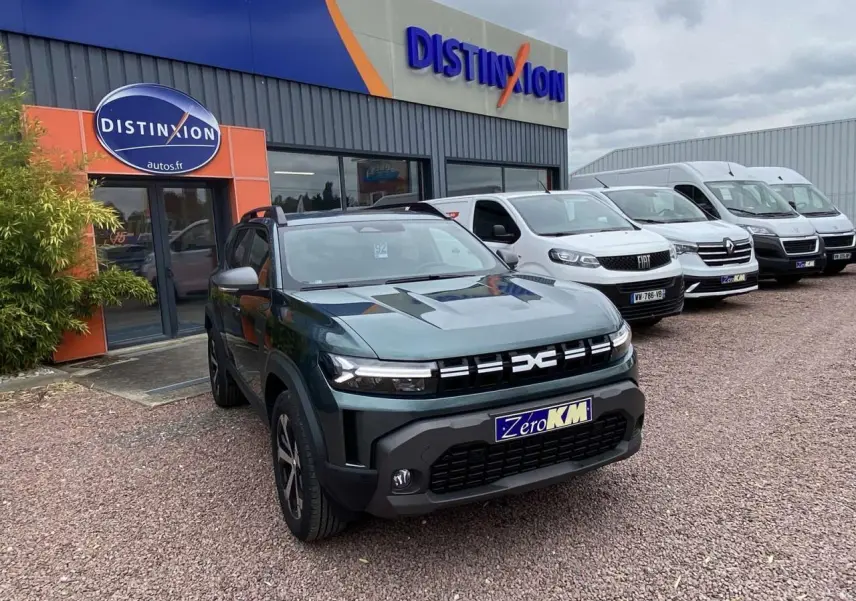 Dacia Duster 1.6 Hybrid 2025 vert INC en 3/4 avant droit, avec calandre moderne et plaques Zero KM visibles.