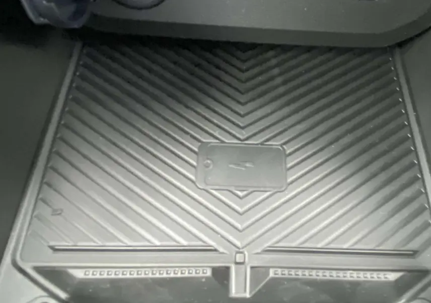 Gros plan sur le tapis de recharge sans fil noir dans l’habitacle du Dacia Duster 1.6 Hybrid 2025.