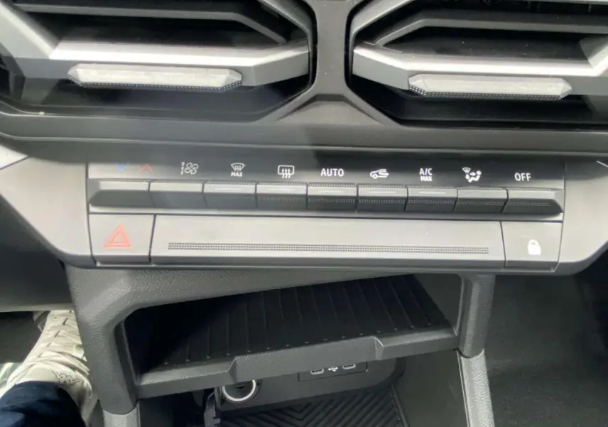 Vue rapprochée de la console centrale du Dacia Duster 2025, avec commandes climatisation et prises USB visibles.