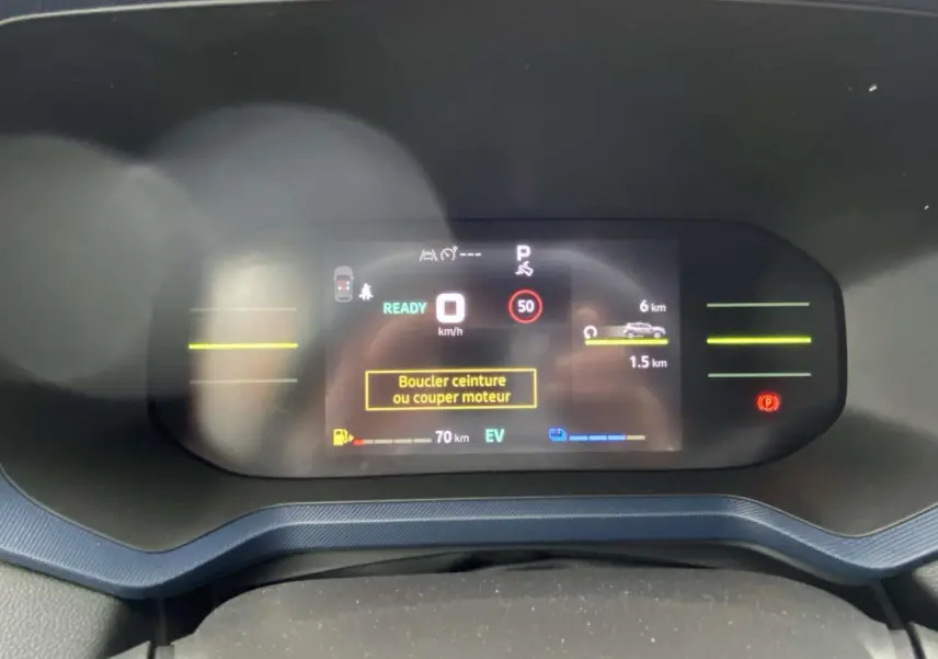 Vue rapprochée du tableau de bord numérique du Dacia Duster 2025, affichant l'écran de conduite en mode hybride.