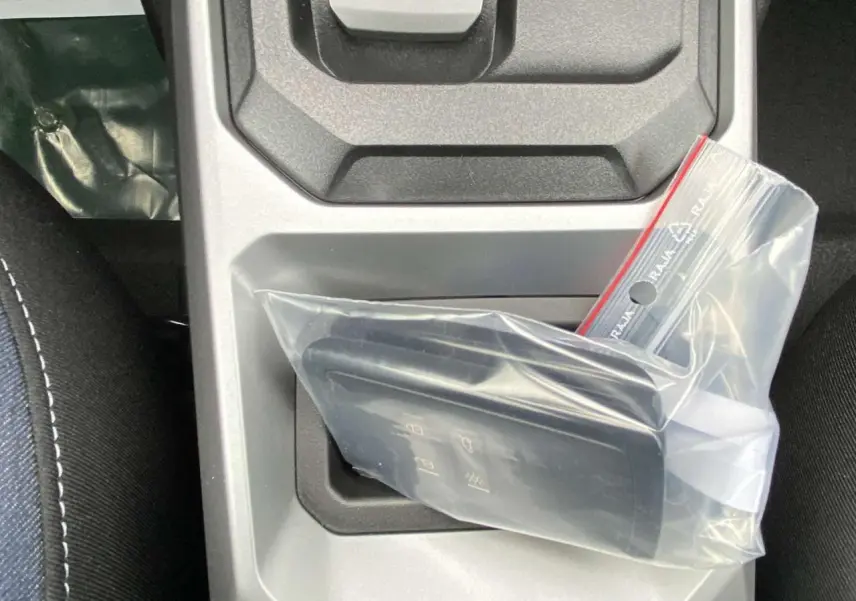 Gros plan sur la clé de la Dacia Duster 1.6 Hybrid 2025 dans un sac plastique, posée sur la console centrale grise.