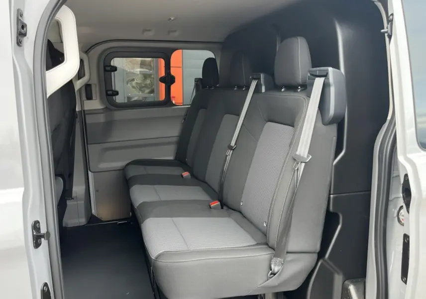 Vue intérieure côté droit du Volkswagen Transporter TDI 170 DSG ProCab L1, sièges arrière gris à trois places avec ceintures.