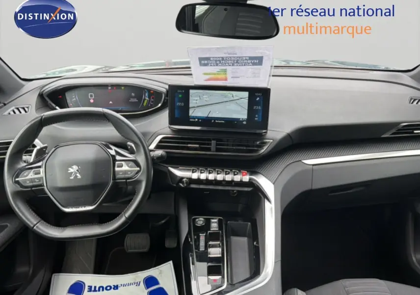 Vue intérieure du tableau de bord du Peugeot 5008 Hybrid 2024 avec écran central tactile et volant compact multifonctions.