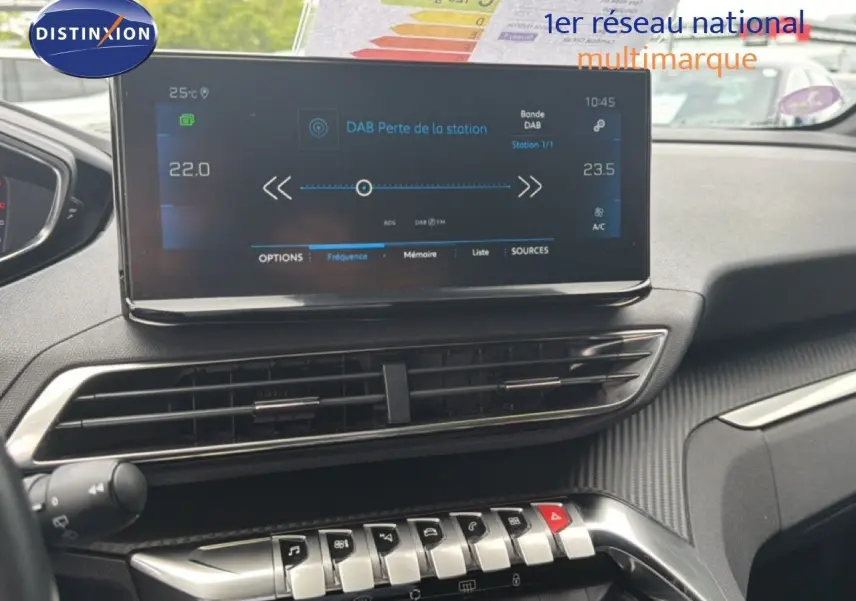 Vue intérieure du tableau de bord du Peugeot 5008 Hybrid 2024, écran tactile et commandes argentées sur fond noir.