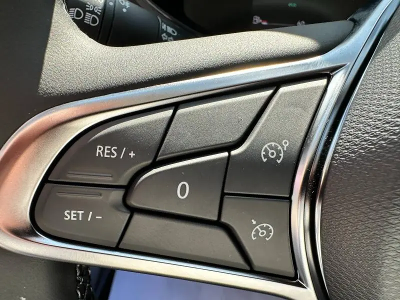 Gros plan sur les commandes du régulateur de vitesse au volant d'une Renault Clio blanche Glacier 2025.