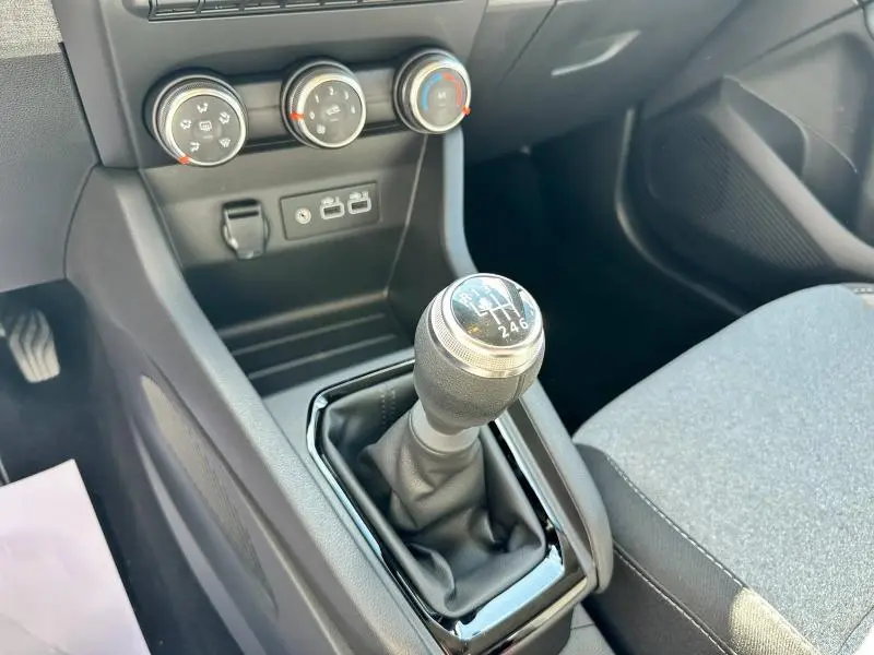 Gros plan sur la console centrale de la Renault Clio 2025 blanc glacier, mettant en valeur le levier de vitesses manuel et les commandes de climatisation.
