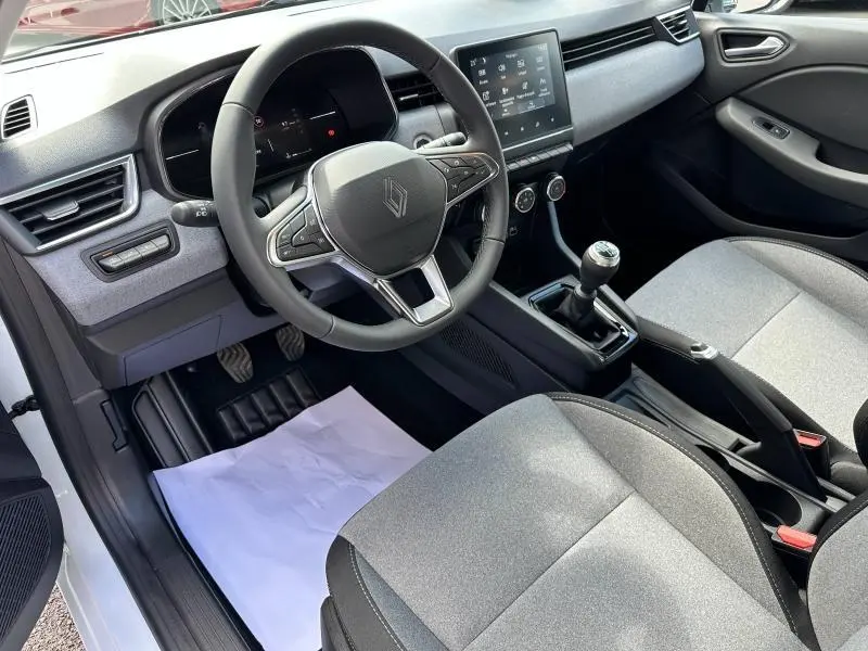 Intérieur avant droit de Renault Clio blanc Glacier 2025, volant multifonction, écran tactile et sièges gris clair.