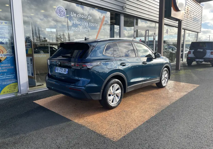 Vue 3/4 arrière droite d'un Volkswagen Tiguan 2024 bleu Nightshade, avec vitres teintées et jantes alliage visibles.