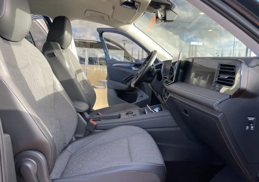 Vue intérieure côté conducteur du Volkswagen Tiguan 2024, sièges gris-noir avec volant cuir et tableau de bord moderne.