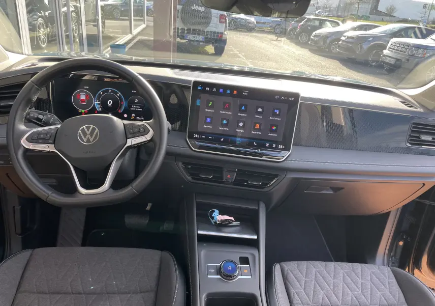 Vue intérieure avant du Volkswagen Tiguan 2024, tableau de bord moderne avec écran tactile et volant multifonction noir.