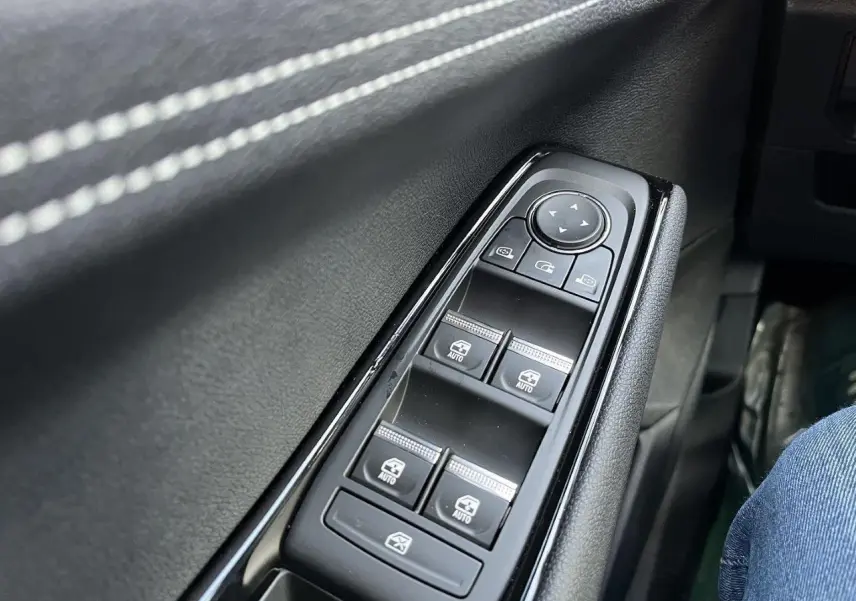 Gros plan sur les commandes des vitres électriques côté gauche d’un Renault Austral gris schiste, intérieur noir.