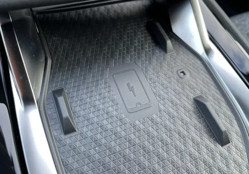 Gros plan sur le chargeur à induction noir au centre de la console intérieure du Renault Austral gris schiste.