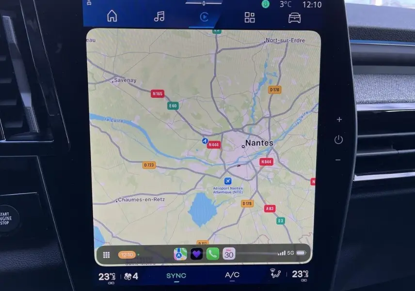 Écran central tactile du Renault Austral Ph.2 gris schiste montrant la navigation GPS sur Nantes, avec commandes climatisation visibles.