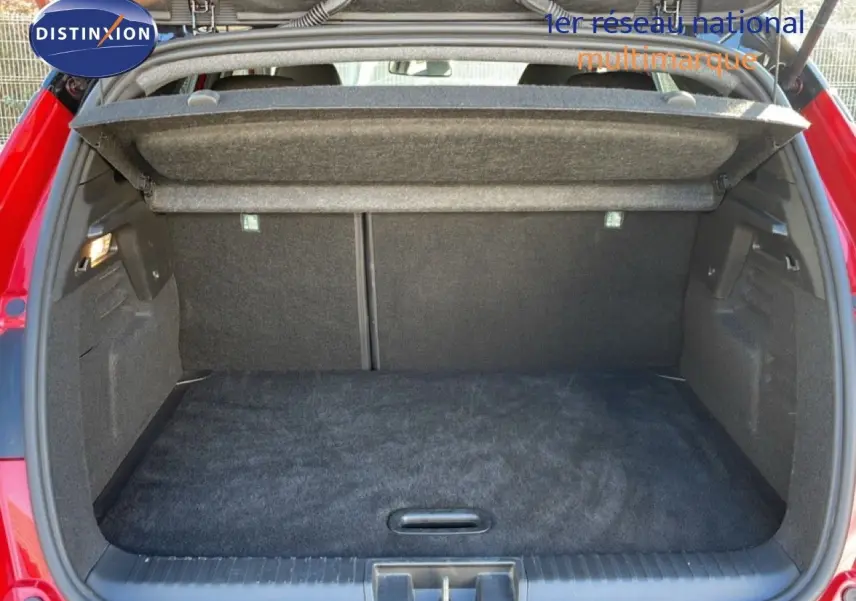 Coffre ouvert vu de l'arrière d'un Renault Captur rouge Désir métal avec toit noir, montrant l'espace de chargement vide.
