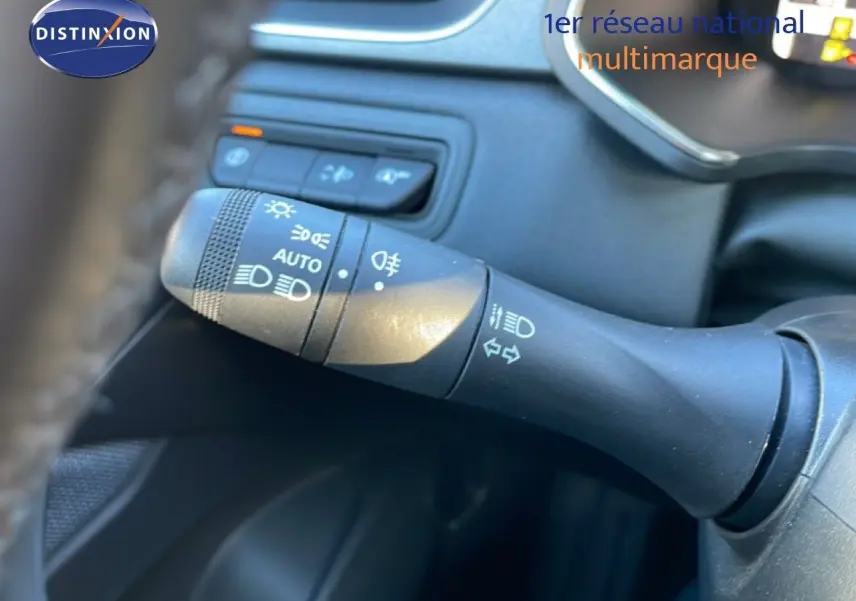 Gros plan sur la commande des feux et clignotants à gauche du volant dans l’habitacle du Renault Captur rouge Désir métal toit noir.