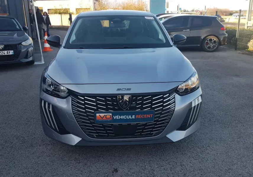 Vue avant frontale d’une Peugeot 208 gris métallisé avec calandre noire et feux diurnes LED distinctifs.
