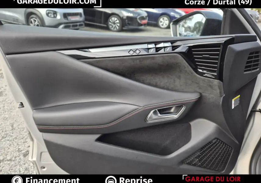 Vue rapprochée de la porte avant gauche beige du DS4 2024 avec garniture noire et surpiqûres rouges visibles.