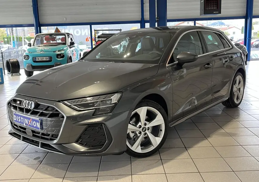 Audi A3 Sportback gris en 3/4 avant droit, avec jantes alliage 5 branches et toit ouvrant panoramique visible en showroom.