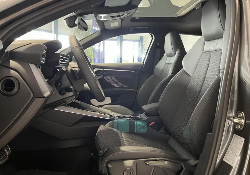 Vue intérieure côté conducteur de l'Audi A3 Sportback gris, sièges sport S line en cuir avec logo S embossé.