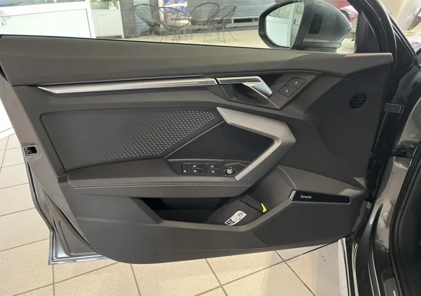 Vue intérieure de la porte avant gauche gris métallisé de l'Audi A3 Sportback 2025 avec finitions S line et haut-parleur Sonos intégré.