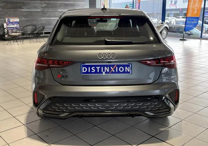 Vue arrière d'une Audi A3 Sportback gris métallisé avec détails S line et feux arrière LED dynamiques en showroom.
