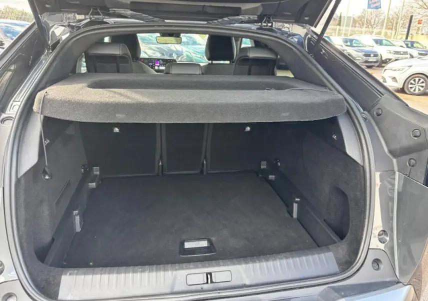 Coffre ouvert du Peugeot 3008 Hybrid gris, vue arrière montrant l’espace de chargement et la plage arrière.