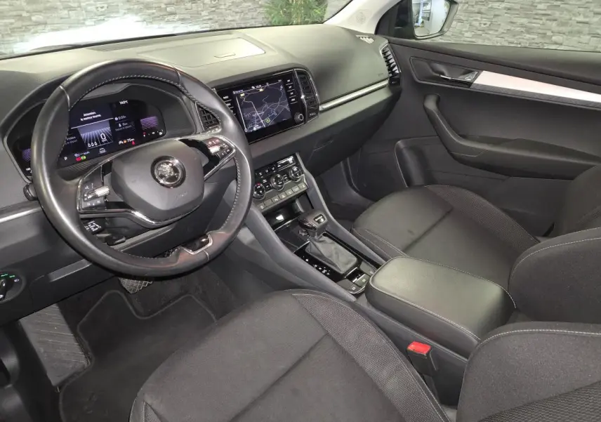 Intérieur avant droit du Skoda Karoq 2024, tableau de bord noir avec écran tactile et volant cuir multifonctions.