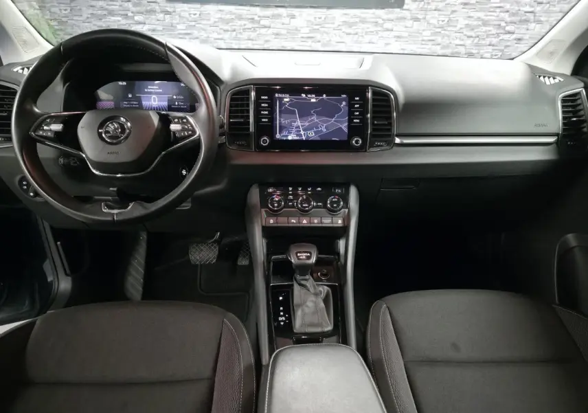 Vue intérieure avant du Skoda Karoq 2024, tableau de bord noir avec écran tactile et volant cuir multifonctions.