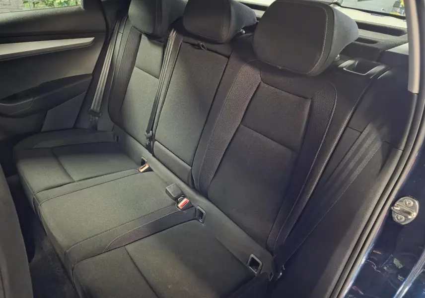 Vue intérieure de la banquette arrière noire du Skoda Karoq bleu, avec trois appuie-tête et ceintures de sécurité visibles.
