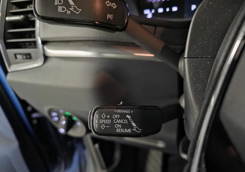 Gros plan sur la commande de régulateur de vitesse à gauche du volant du Skoda Karoq bleu 2024.